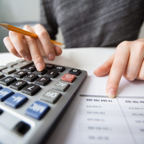 Closeup of accountant counting on calculator and working with table